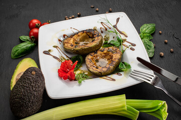 Juicy grilled avocado with sauce and herbs on wooden background