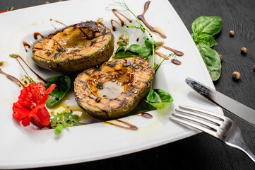 Juicy grilled avocado with sauce and herbs on wooden background