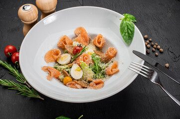 Dish of salmon with eggs, herbs and salad on wooden background