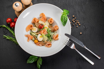 Dish of salmon with eggs, herbs and salad on wooden background