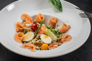 Dish of salmon with eggs, herbs and salad on wooden background