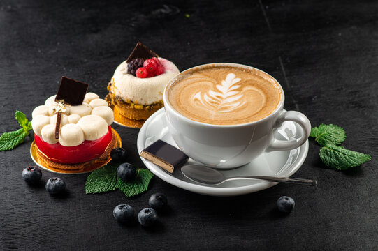 Cup of capuccino and cupcakes on wooden background