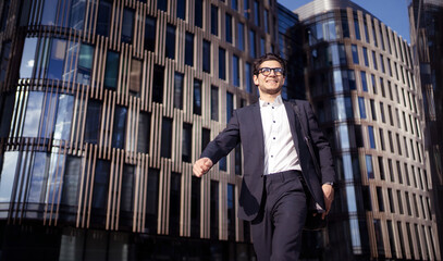 A male manager an employee of a company with glasses goes to the office in a business suit