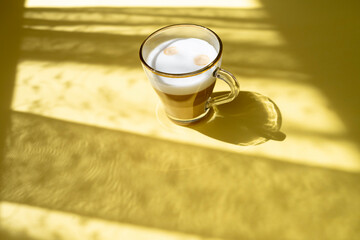cup of coffee in morning light, sunlight shadow, morning breakfast concept, top view on yellow background