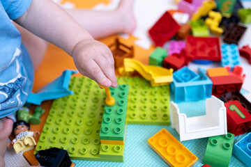 Close-up of a child's hands playing with toys and plastic bricks. The concept of early development.