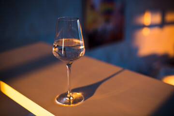 A glass of wine, water, lights up, glares against the background of the setting sun. Sunset in a glass.