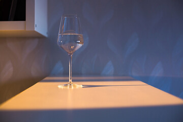A glass of wine, water, lights up, glares against the background of the setting sun. Sunset in a glass.