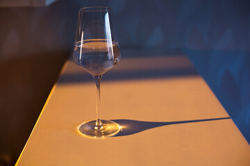A glass of wine, water, lights up, glares against the background of the setting sun. Sunset in a...