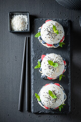 Tasty sushi burger with sesame and berries sprinkled with seeds.