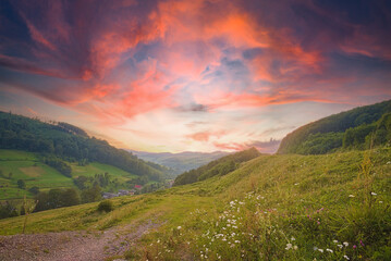 Fototapeta na wymiar beautiful sunrise in the mountain area. the sky plays with warm colors. hills with fields and forests. countryside. summer season. Breathtaking nature scenery during sunset. 