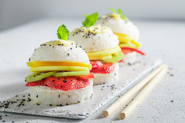 Sweet sushi burger with strawberries and mango on white plate.