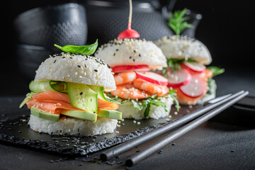Delicious sushi burger with seafood and rice on strone plate.