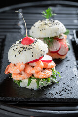 Tasty sushi burger with avocado and salmon on strone plate.