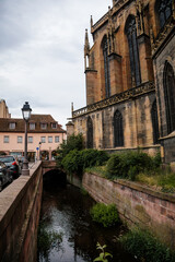 Colmar, Alsace, France, 4 July 2022: town capital of Alsatian wine, narrow picturesque street with medieval colorful houses, Roman Catholic Gothic St Martins Church with tower at summer day