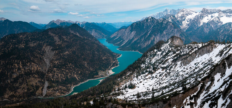 Turquoise colored Lake Plansee with mountains in Tyrol Austria during sunny blue sky weather from above.