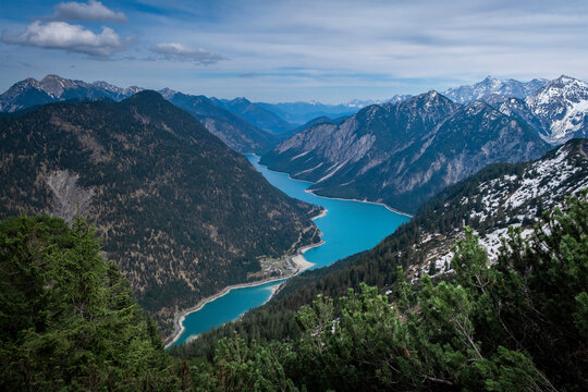 Turquoise colored Lake Plansee with mountains in Tyrol Austria during sunny blue sky weather from above.