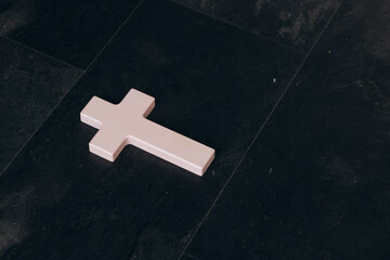 Christian cross on a textured black background. Religion concept. Pink cross