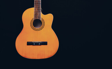 Obraz premium Six-string acoustic guitar on a dark brown background. Classical Spanish guitar. Musical instrument. Place for text.