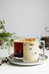 Two cups of coffee. Hot coffee in the background, coffee ice with milk in the foreground (a coffee drink made from ice cubes of coffee). Close-up.