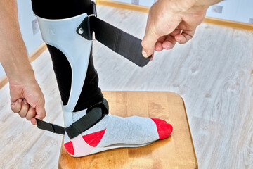 Ankle foot orthosis brace is fixed on leg with velcro straps.
