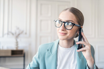 Portrait of a freelancer a woman with glasses working in an office talking on the phone