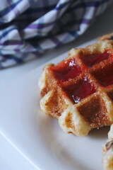 Waffles topped with chocolate and strawberries served in a white plate.