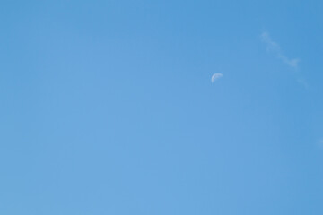 Blue sky background and white clouds soft focus, pastel sky. The moon is high in the sky.