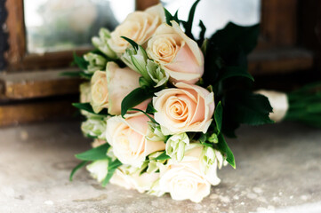 Wedding bouquet with white roses lies on the windowsill of the window