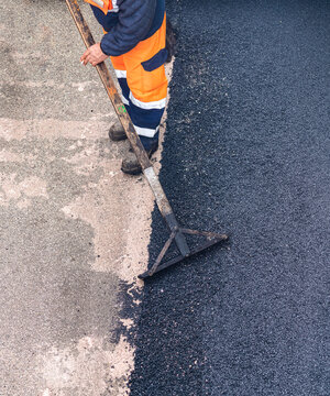 Worker on Asphalting paver machine during Road street repairing works