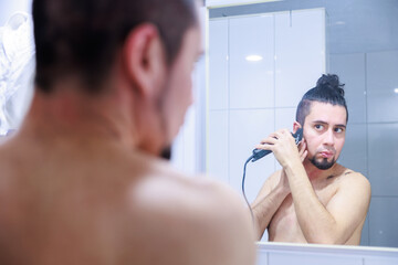 鏡に映るラテン系の男性、髭をカットして整える