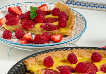 Round quiche with red strawberries and raspberries on a white table