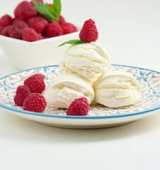 Vanilla ice cream balls with red raspberries in a round plate