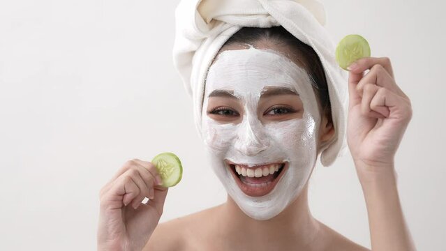 Beauty concept of 4k Resolution. Asian girl putting cucumber at her eyes on a white background.