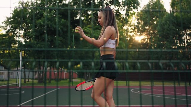 alluring young woman is training on tennis court in summer morning, walking on sporty ground