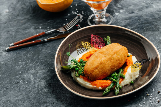 Chicken Kiev cutlet breast stuffed with butter, garlic and herbs served with asparagus and peas. Food recipe background. Close up