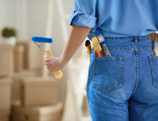 Pretty woman painting interior wall of home with paint roller