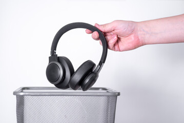 The man throws the headphones in the trash for disposal and recycling