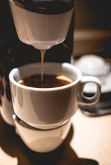 Detail of modern home coffee machine making a coffee in a white cup under interior light 