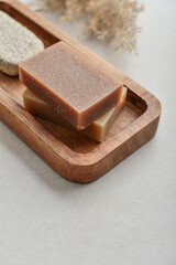 Natural soap bars and pumice stone on wooden tray
