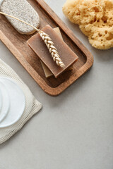 Natural soap bars, wheat spikelet and pumice stone on wooden tray