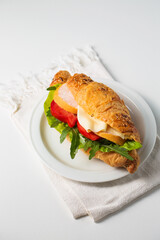 Crispy croissant with ham, cheese and vegetables on a plate