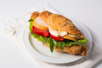 Crispy croissant with ham and vegetables on a plate