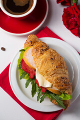 Crispy croissant with ham and vegetables with a cup of coffee, top view