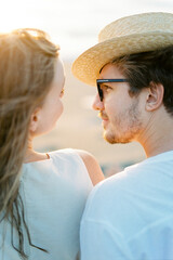 Man in a straw hat and glasses looks at a woman smiling. Back view. Close-up