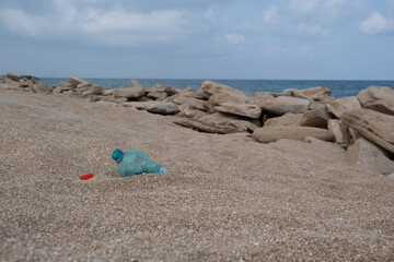 Garbage on a beach left by holiday-makers, environmental pollution concept picture. Sand, sea, sky and recycle trash. Harm to ecology, environmental damage. Convert waste into reusable material.