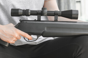 A young woman with a gun in her hands. A woman is holding a large sniper rifle, close-up. Air rifle...