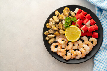 Seafood charcuterie - shrimps, mussels and crab sticks in plate, bright background, top view.