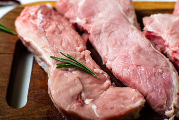 Raw meat steaks on a cutting board. White background. Preparation for cooking pork meat. Various spices, seasonings lie nearby.