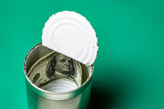 Dollars in an open tin can. Safeguarding cash, stash concept. Time to get the deferred, accumulated money. Green background.
