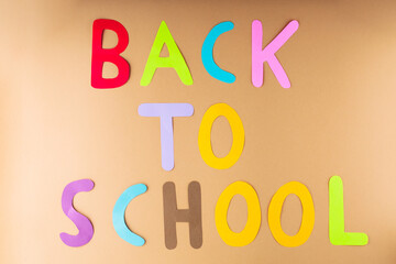 Back to school on a beige background. Inscription Back to school with hand-cut paper letters. Education concept